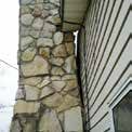 a stone chimney on the side of a house next to a window .