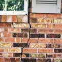 brick house wall with a large crack up it