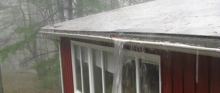 rain is falling from the roof of a red house .