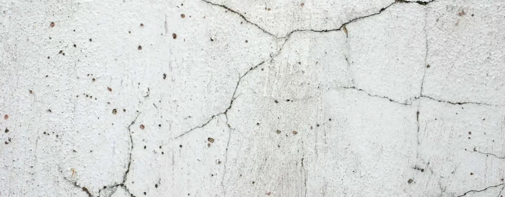 a close up of a white wall with cracks in it .