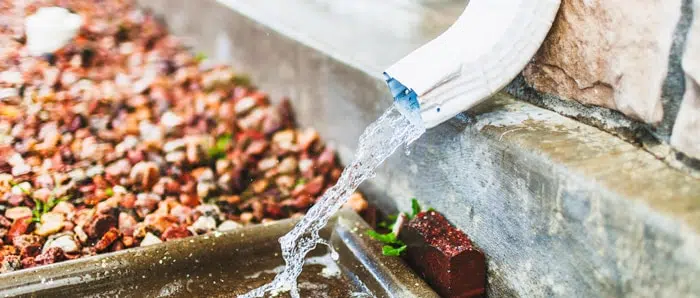 water is pouring out of a gutter into a drain .