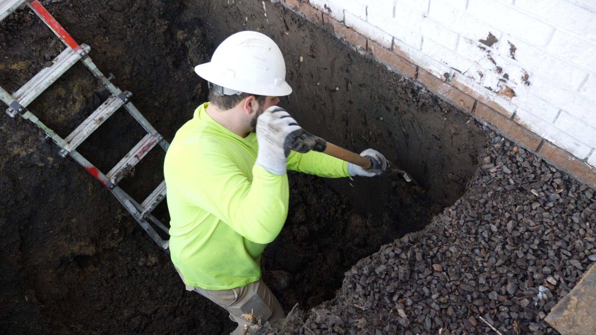 a man wearing a hard hat is digging a hole