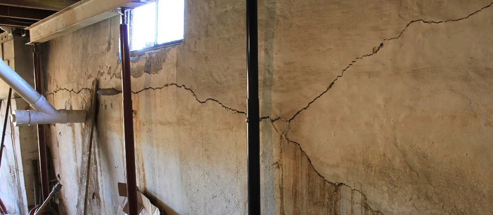 a cracked wall in a basement with a window