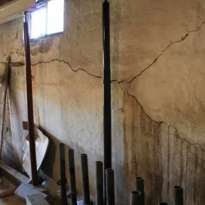a cracked wall with pipes and a window