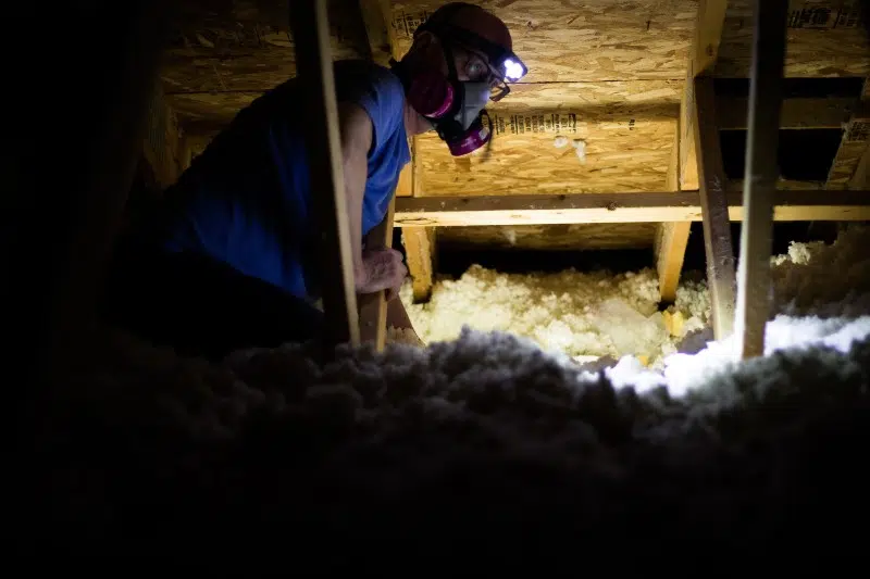 a man wearing a gas mask is working in an attic