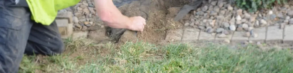 a man is digging a hole in the grass with a shovel .
