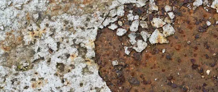 a close up of a piece of rusty metal next to a piece of concrete .